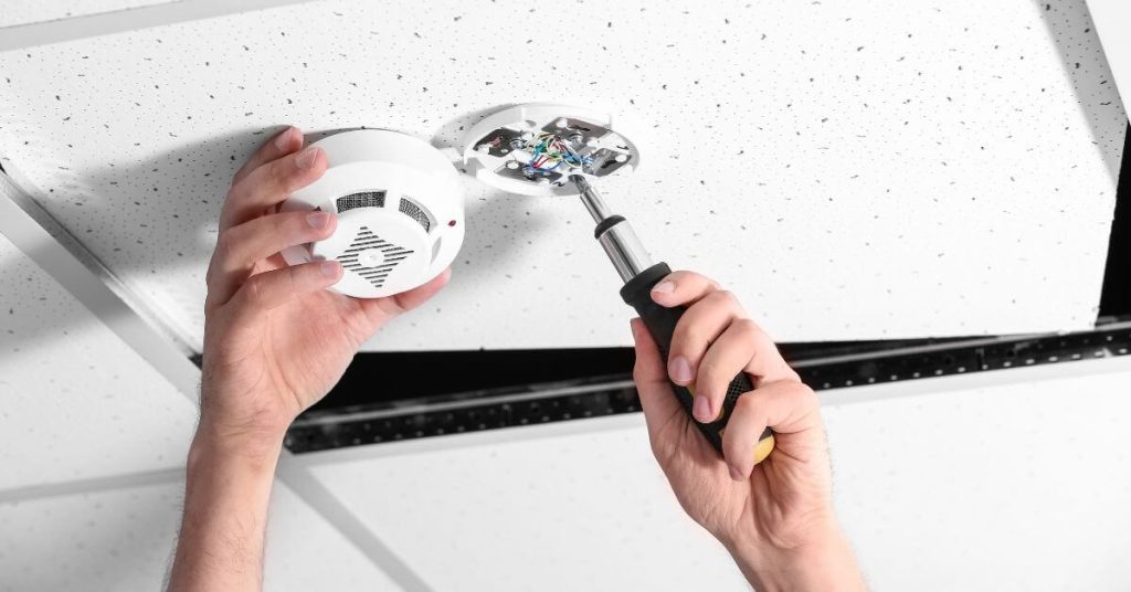 Electrician installing a hard-wired smoke alarm.